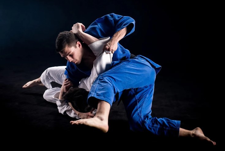 Two grapplers practicing jiu jitsu in a blue and white gi