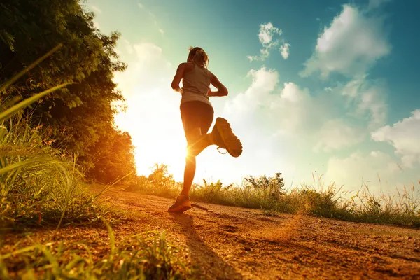 Woman running on a dirt path in the sun