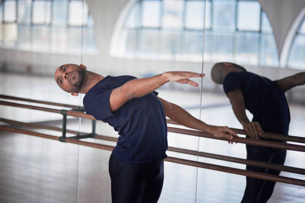Man doing cambré at the barre in a dance studio