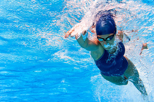 Woman swimming the crawl in a swimming pool with goggles and swim cap