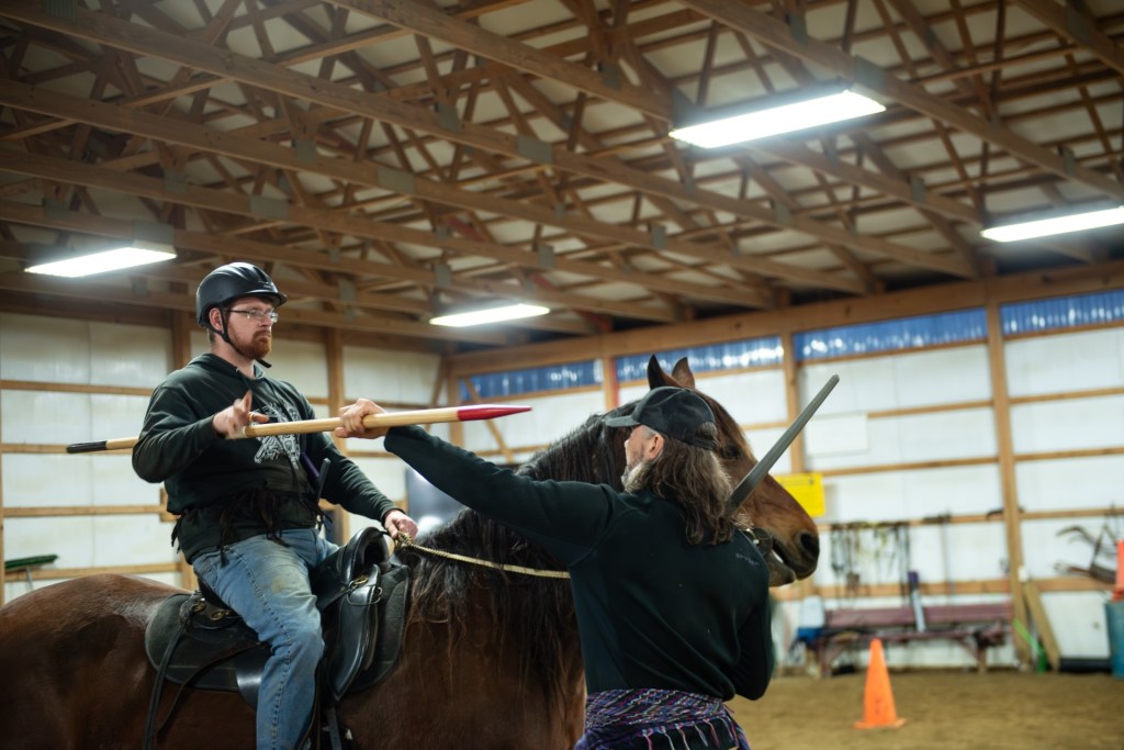 An infantryman on the right takes the lance from a lancer on the left. The infantryman has a sword and is ready to strike. The lancer is letting go of the lance. 